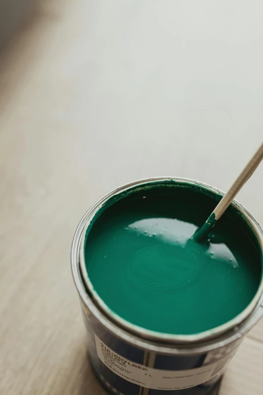 a can of green paint with a wooden spoon in it