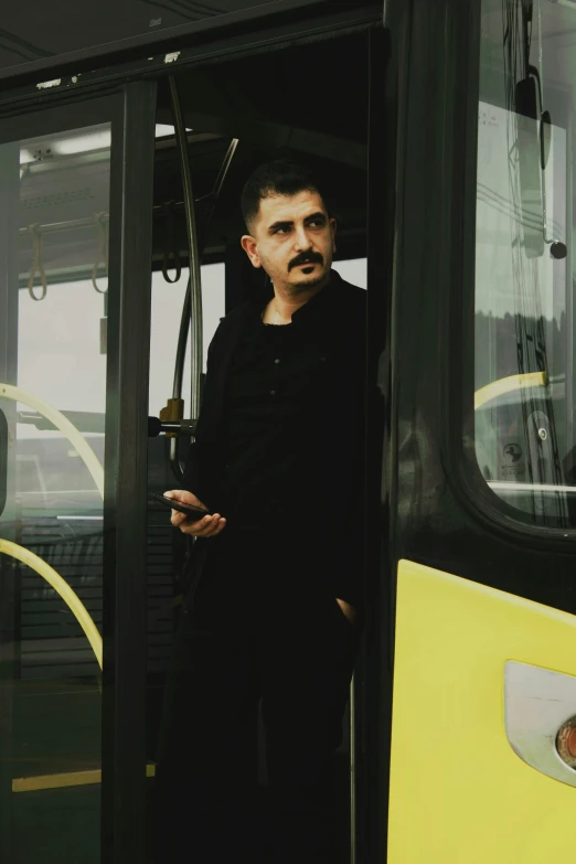 a man standing in the door of a bus, holding a drink