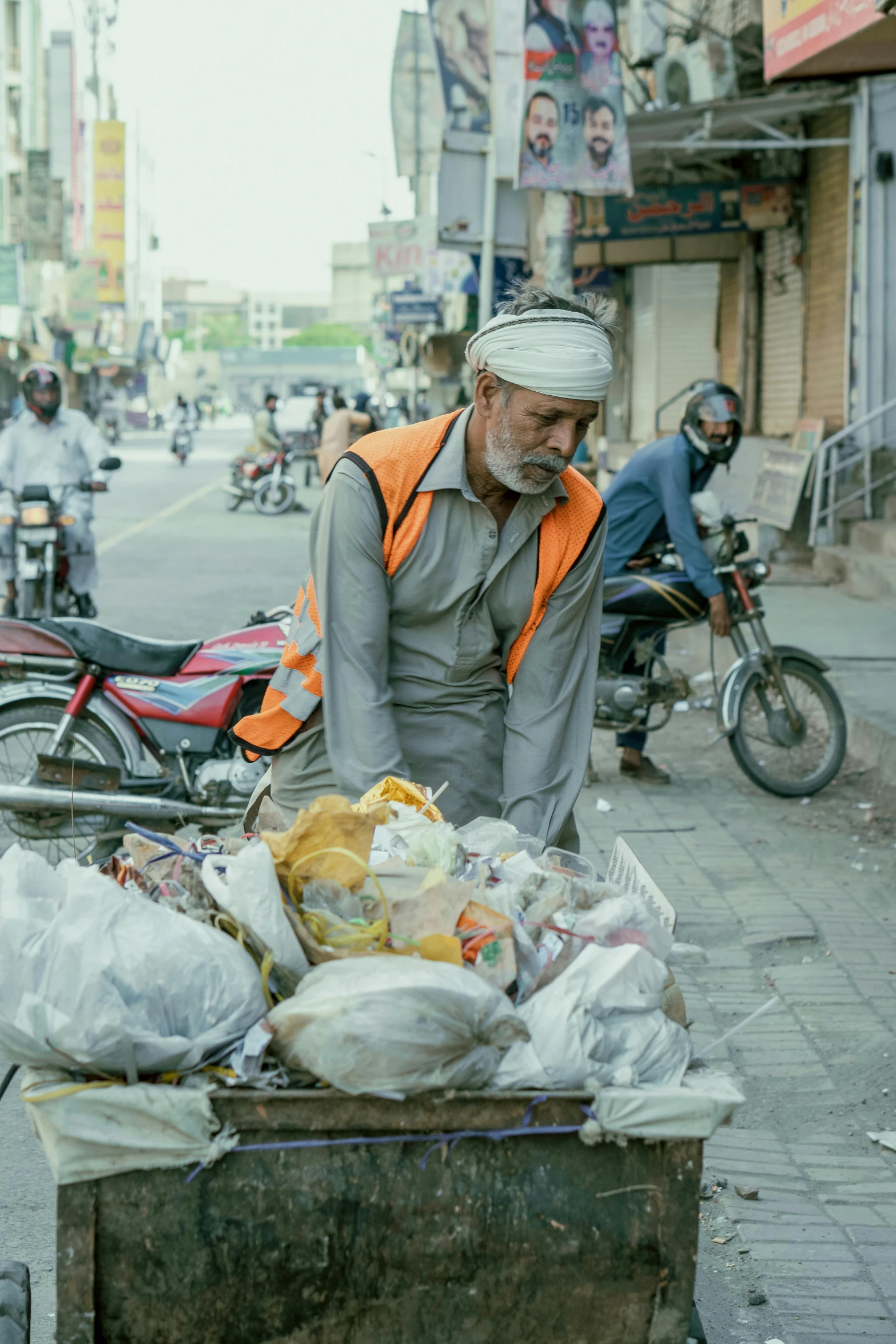 an elderly man hes a cart full of plastic bags down the street