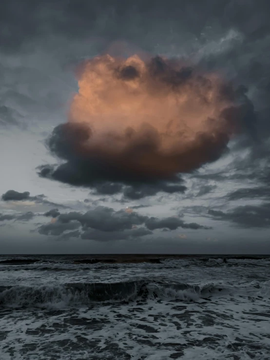 a beach area with waves, a bench and clouds