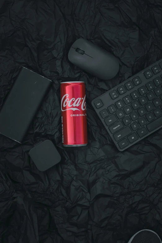 a coca - cola can and keyboard on a bed next to it