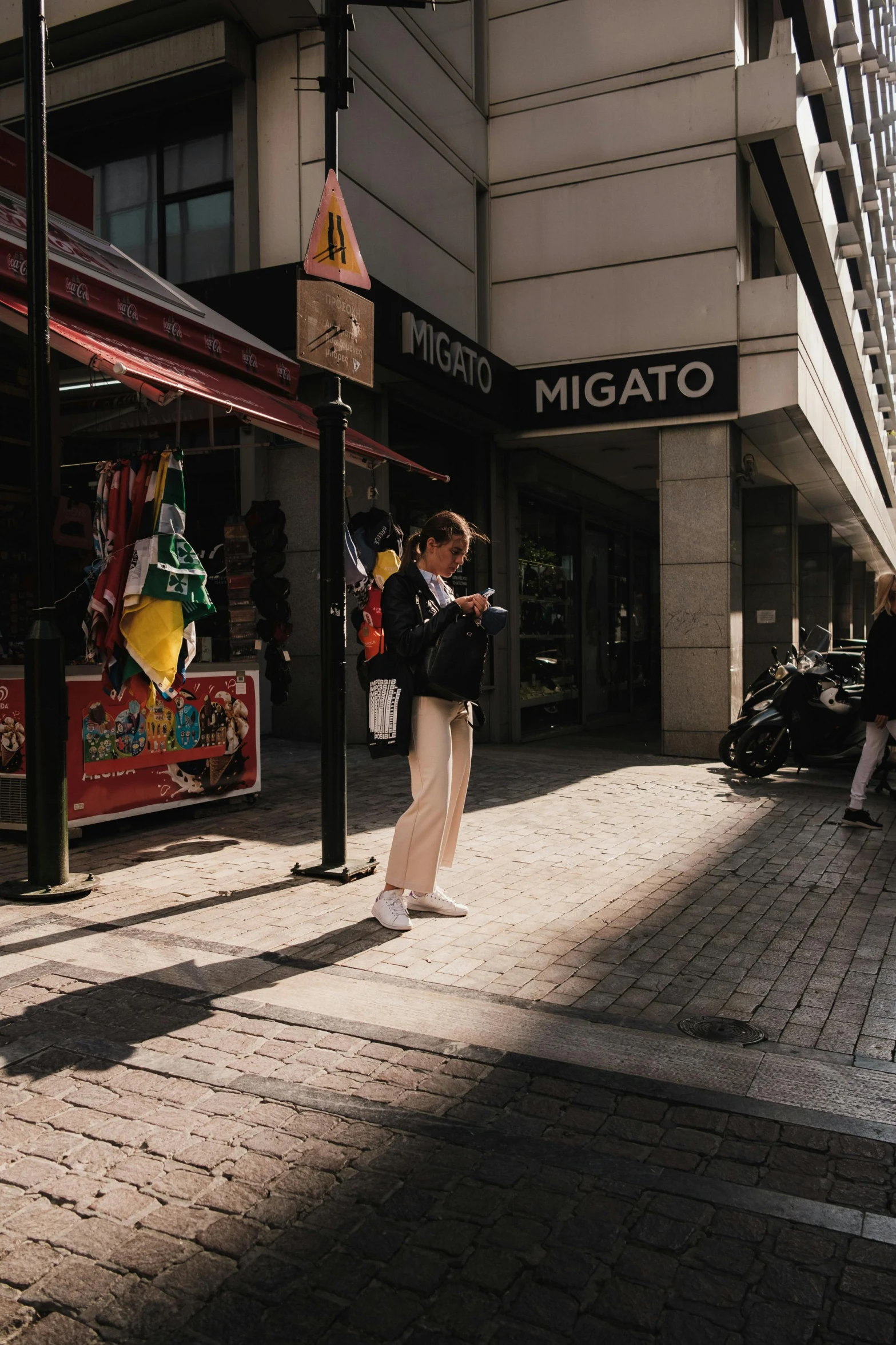 a young woman standing on the side walk holding her suitcase