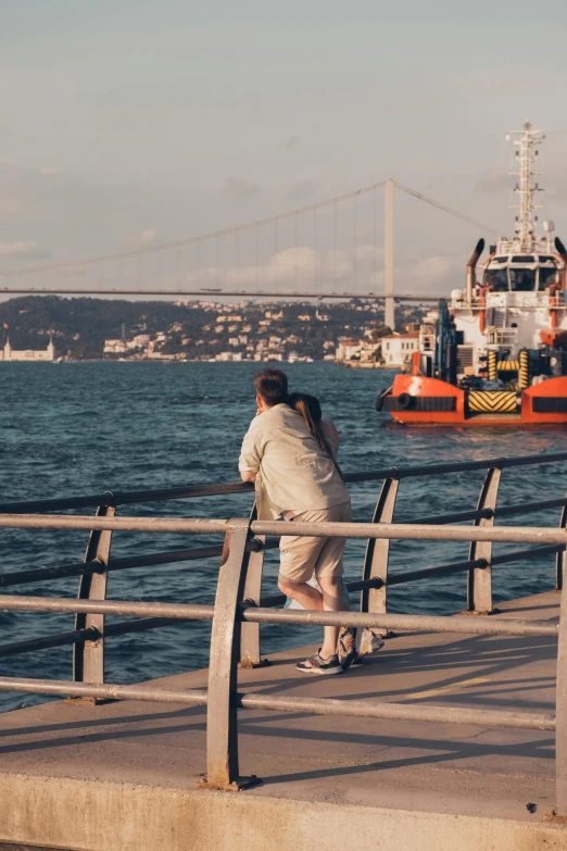 a man and a woman standing by the side of the river on a pier