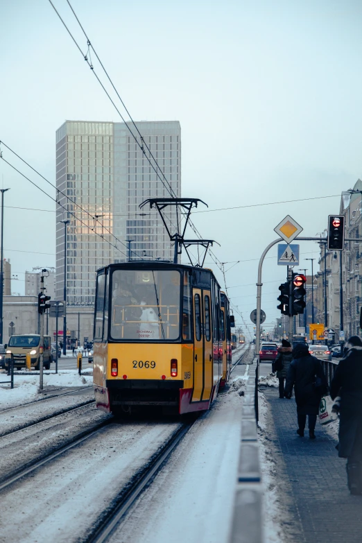 yellow train passing through the city in a snowy day