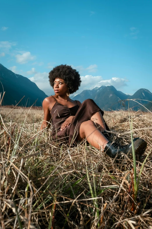 a black woman is sitting on the grass looking up at soing