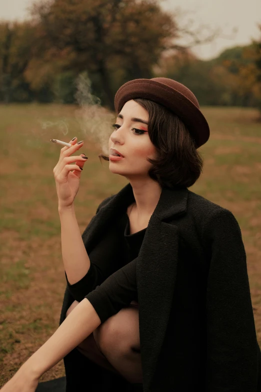 a woman smoking a cigarette in the grass