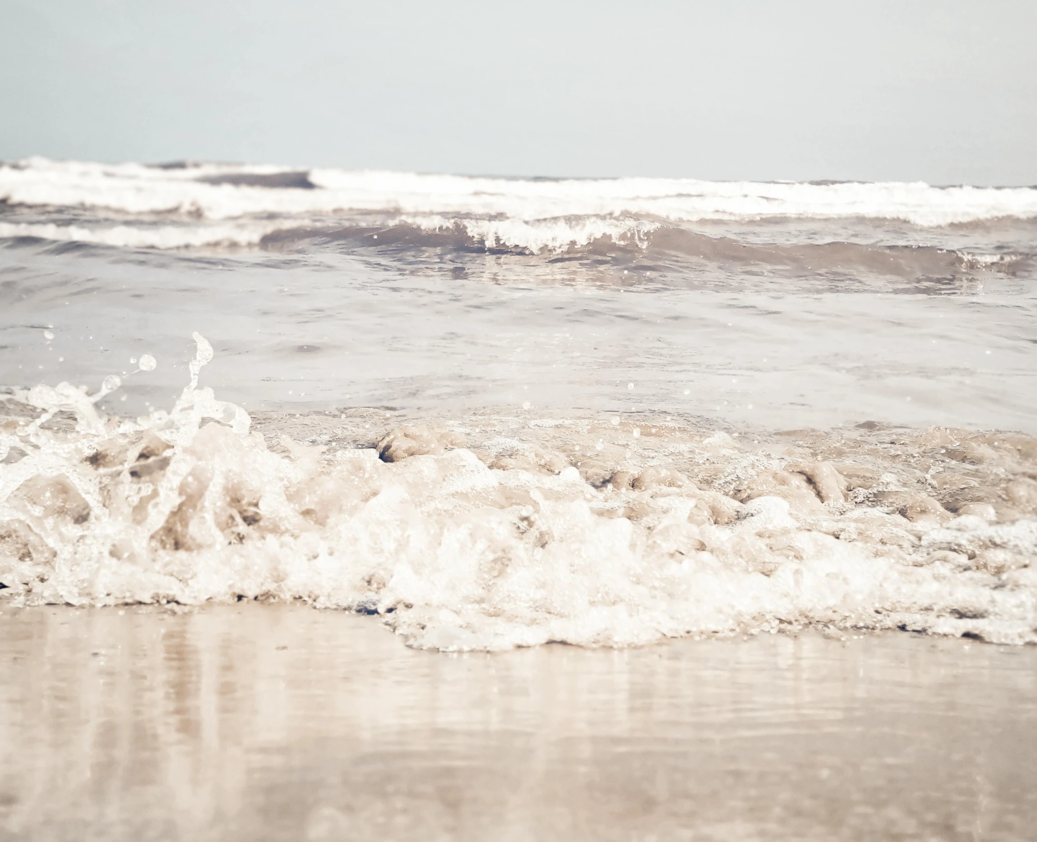 waves roll in towards the beach shore