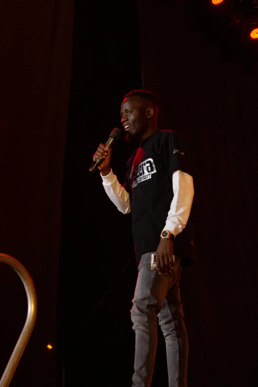 a man standing up with a microphone on a stage