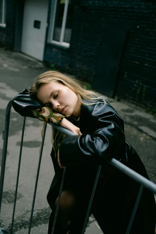 the woman is leaning on a fence holding her head