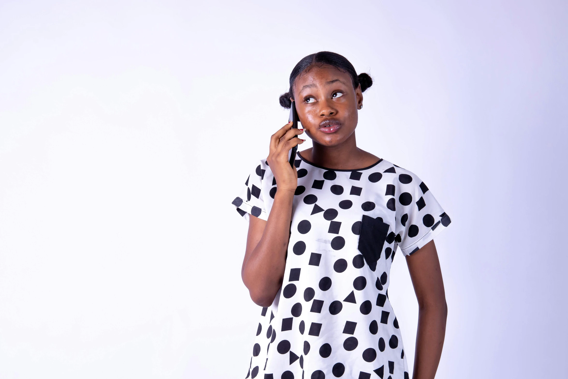 a woman is holding a cell phone to her ear and standing against a white background