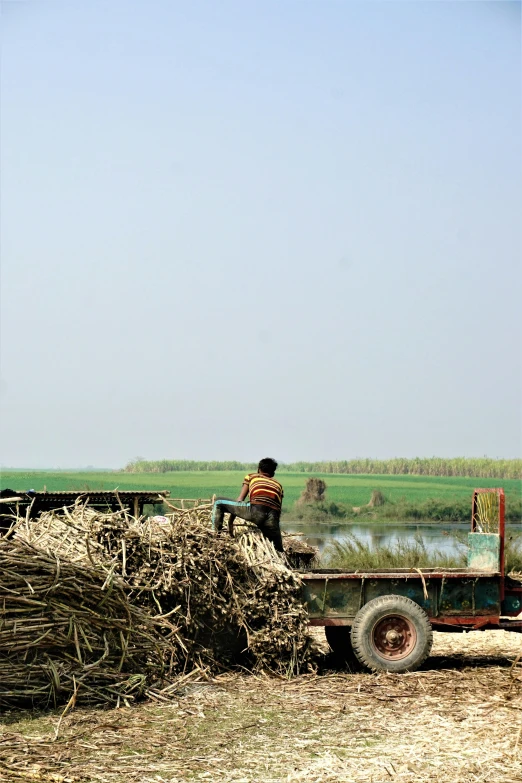 an old green pickup truck towing a trailer full of hay