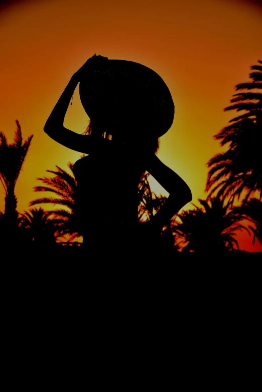 a silhouette of a woman with her hat on