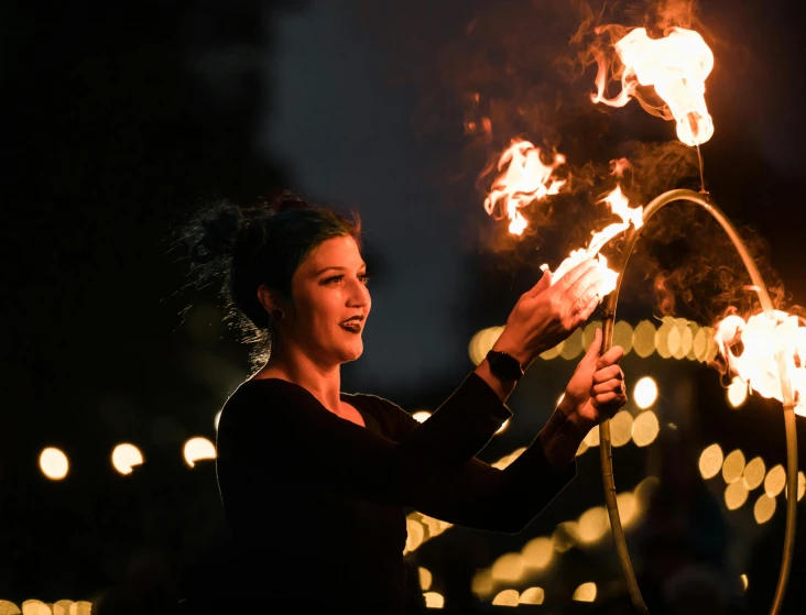 a woman holding fire hose at night, using torches