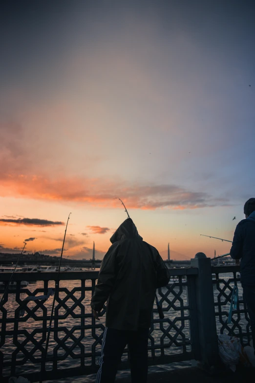 three people are standing on the edge of a bridge watching a fish