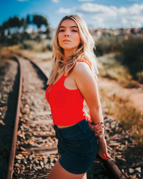 a young blond woman in a red shirt is holding a suitcase