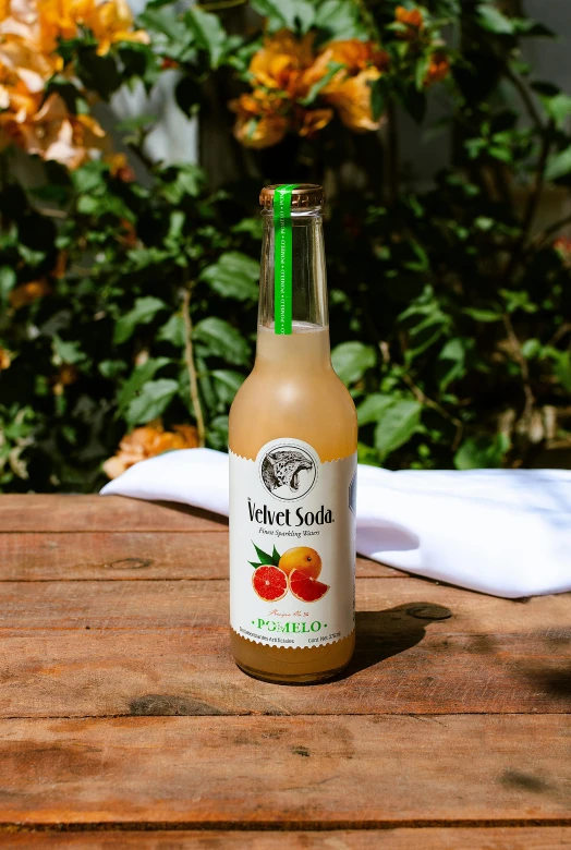 a bottle of fruit soda sitting on a wooden table