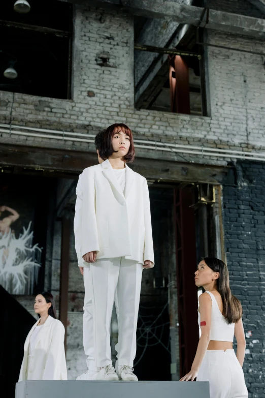 a person standing on a stage while wearing a white outfit