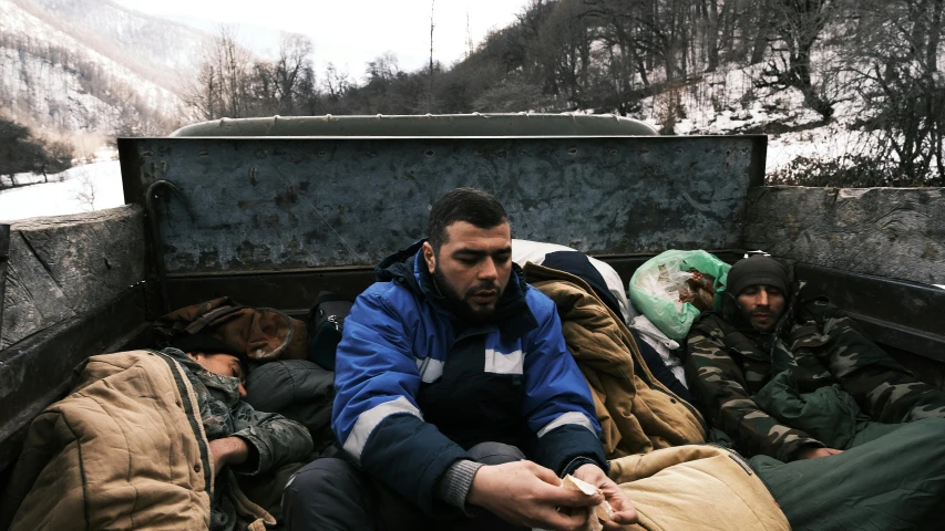 a group of men sleeping in bed with snow on the hill behind them