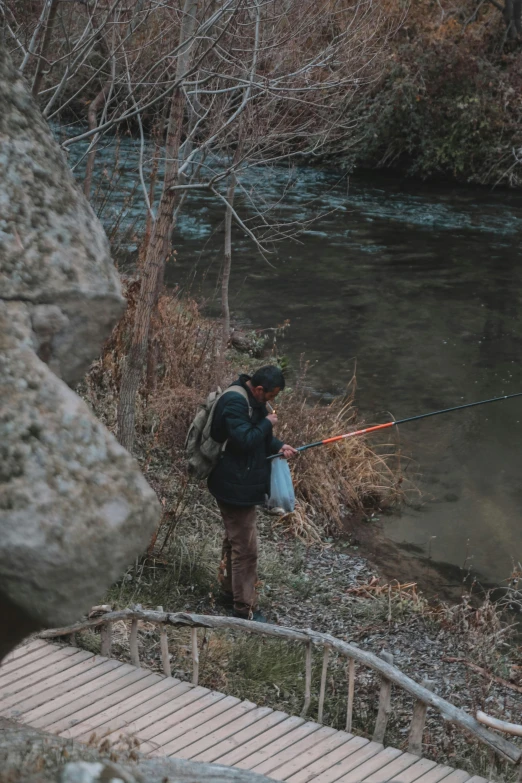 a man is standing on a boardwalk, holding a fishing rod