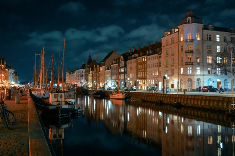 a night scene with sailboats moored on a canal