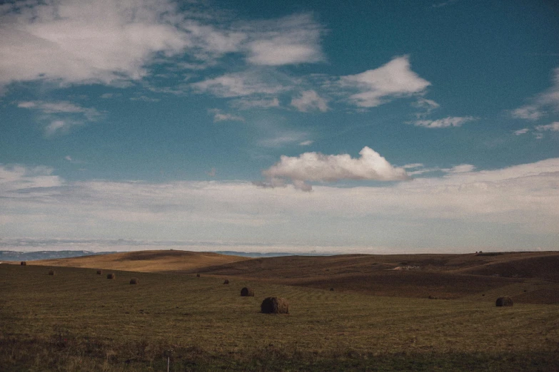 a very wide open field with grass and hills