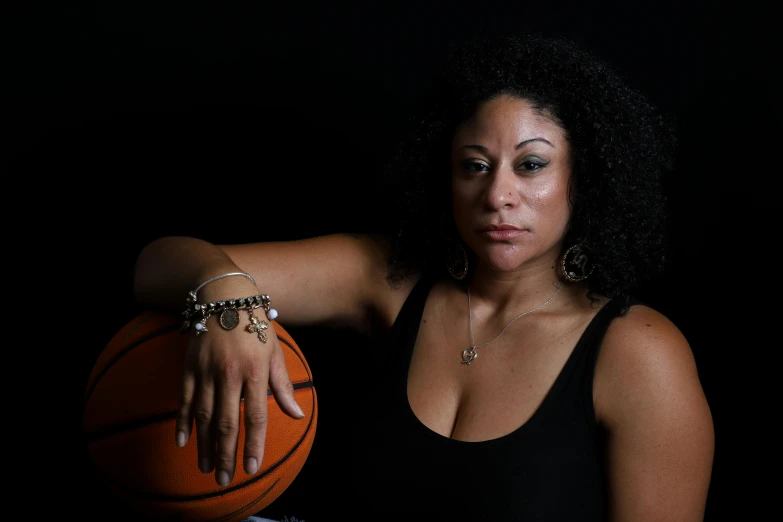 woman with black dress and celet holding basketball