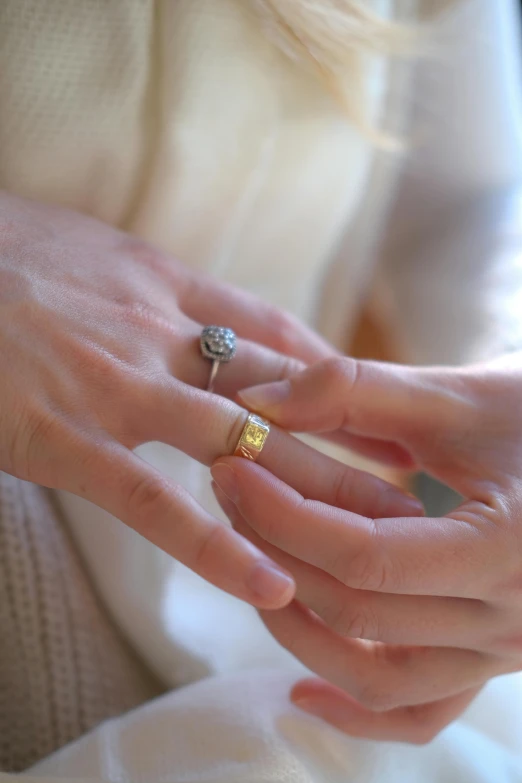 the woman's fingers are touching her gold diamond ring