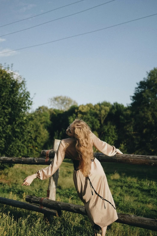 a woman leaning over a fence on her knees