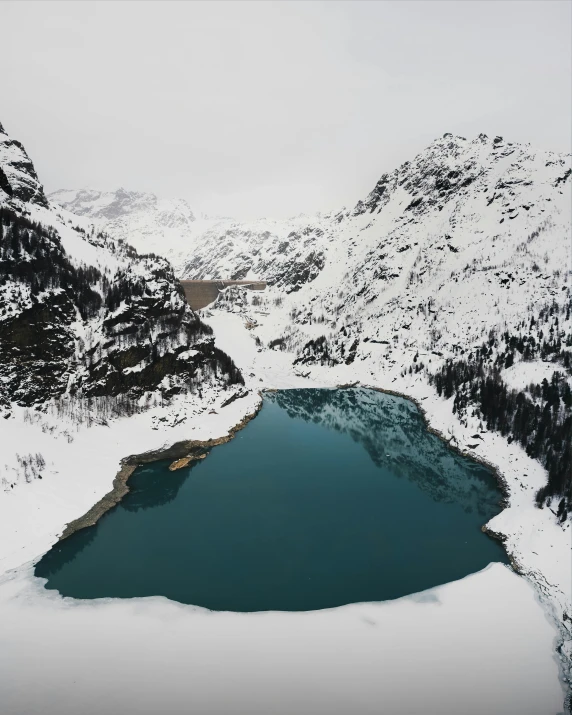 a lake with a small patch of water next to it and snow covered mountains in the background