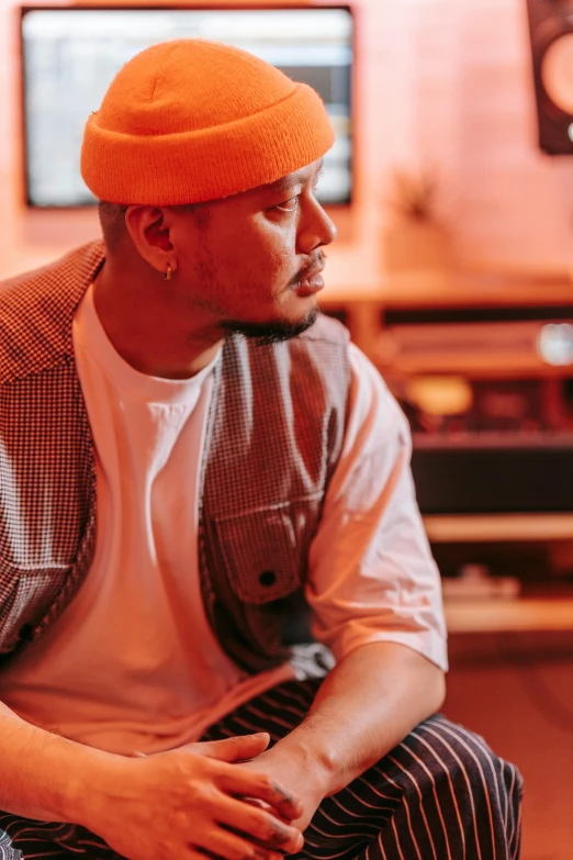 the man is sitting down while wearing a orange hat