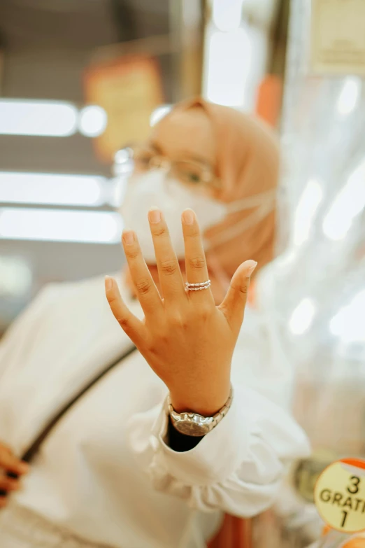 a woman in a white lab coat and face mask waves