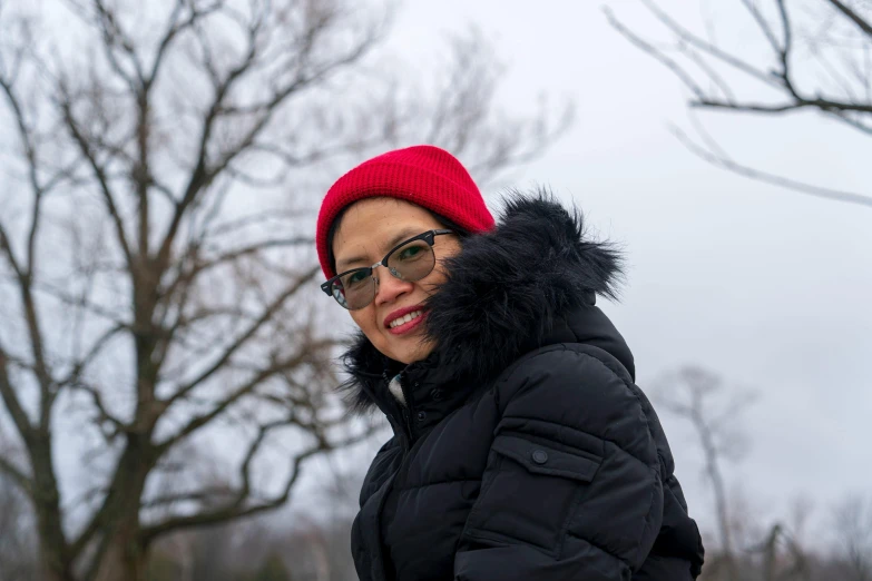 a woman wearing glasses, a black jacket and a red hat