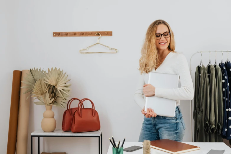 a smiling woman holding a laptop in her hand