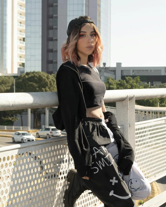 a woman with pink hair stands on a fence