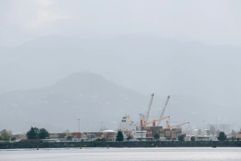 large cranes and houses in the distance near water