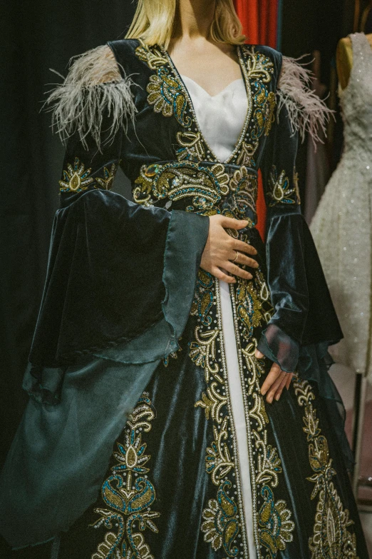 a woman in a blue and gold gown wearing fur trimmed gloves