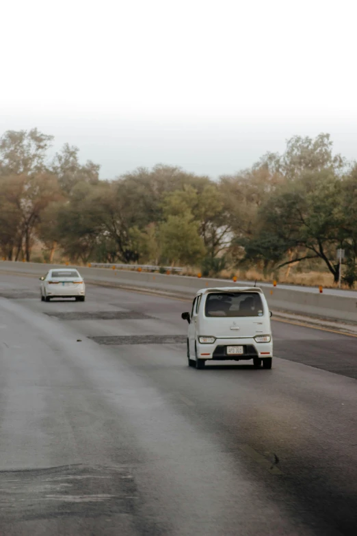 two cars driving on an empty highway near trees