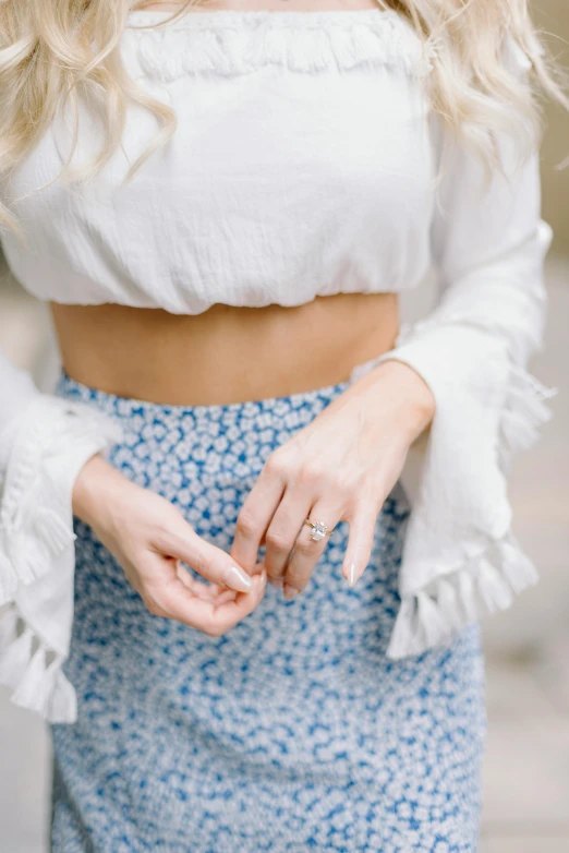 a woman with blonde hair wearing a white top and blue skirt