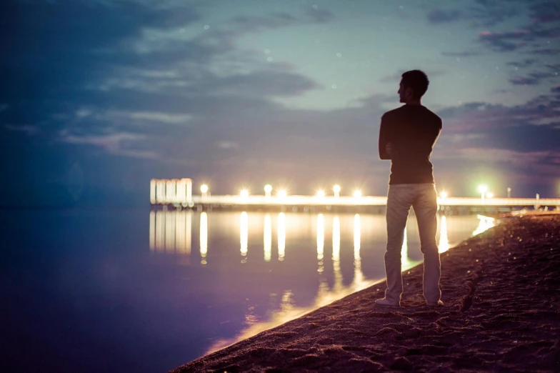 a man stands on the shore of a lake watching soing