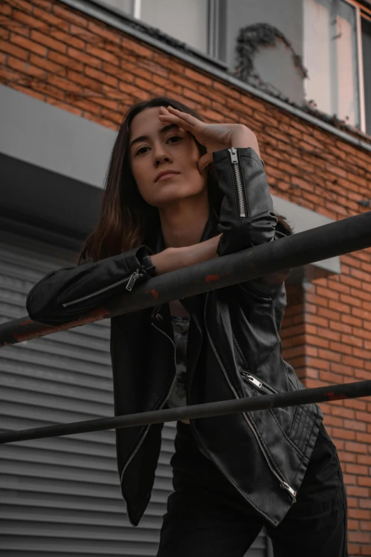 woman in a leather jacket leaning against a building