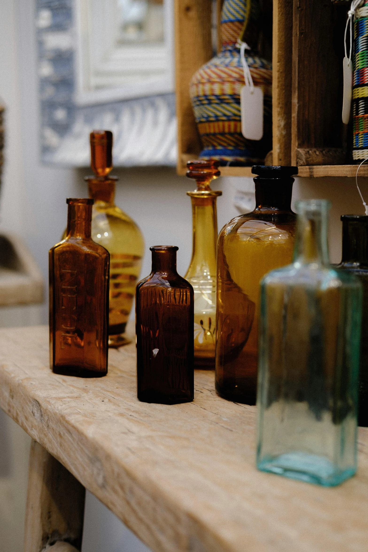 various colored glass vases are displayed on a wood shelf