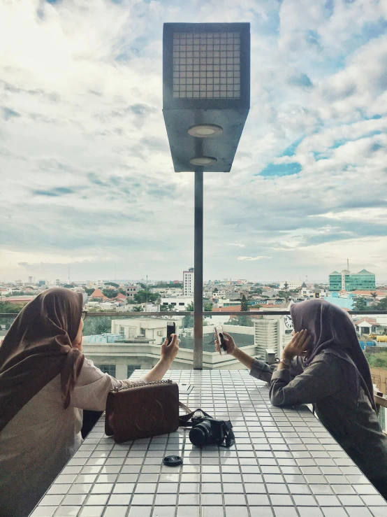 two girls sitting at a table with a view of the city