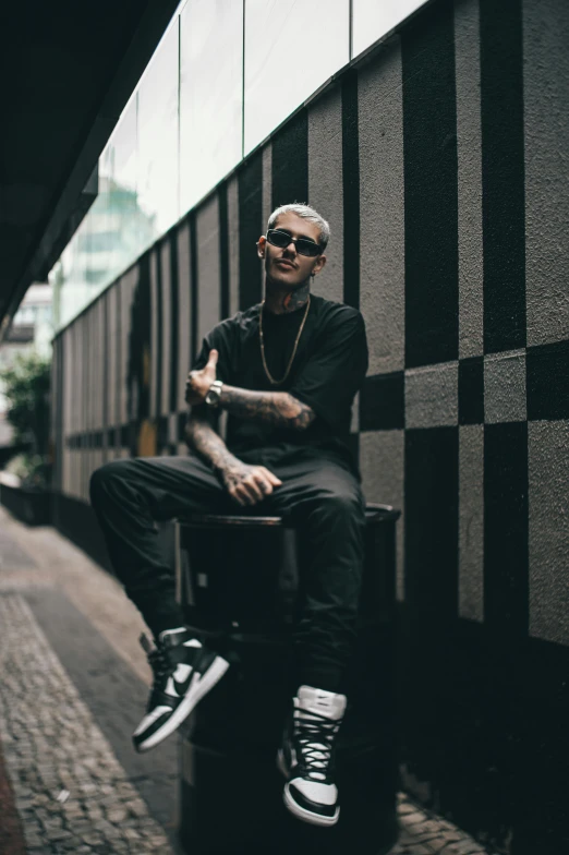 man with tattoos and shades sitting on bench outdoors