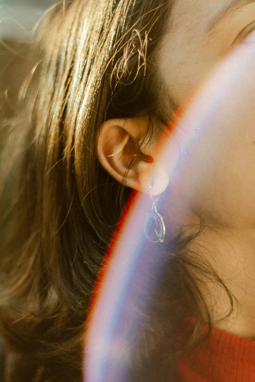 a woman holds her ear with the light reflecting from the ceiling