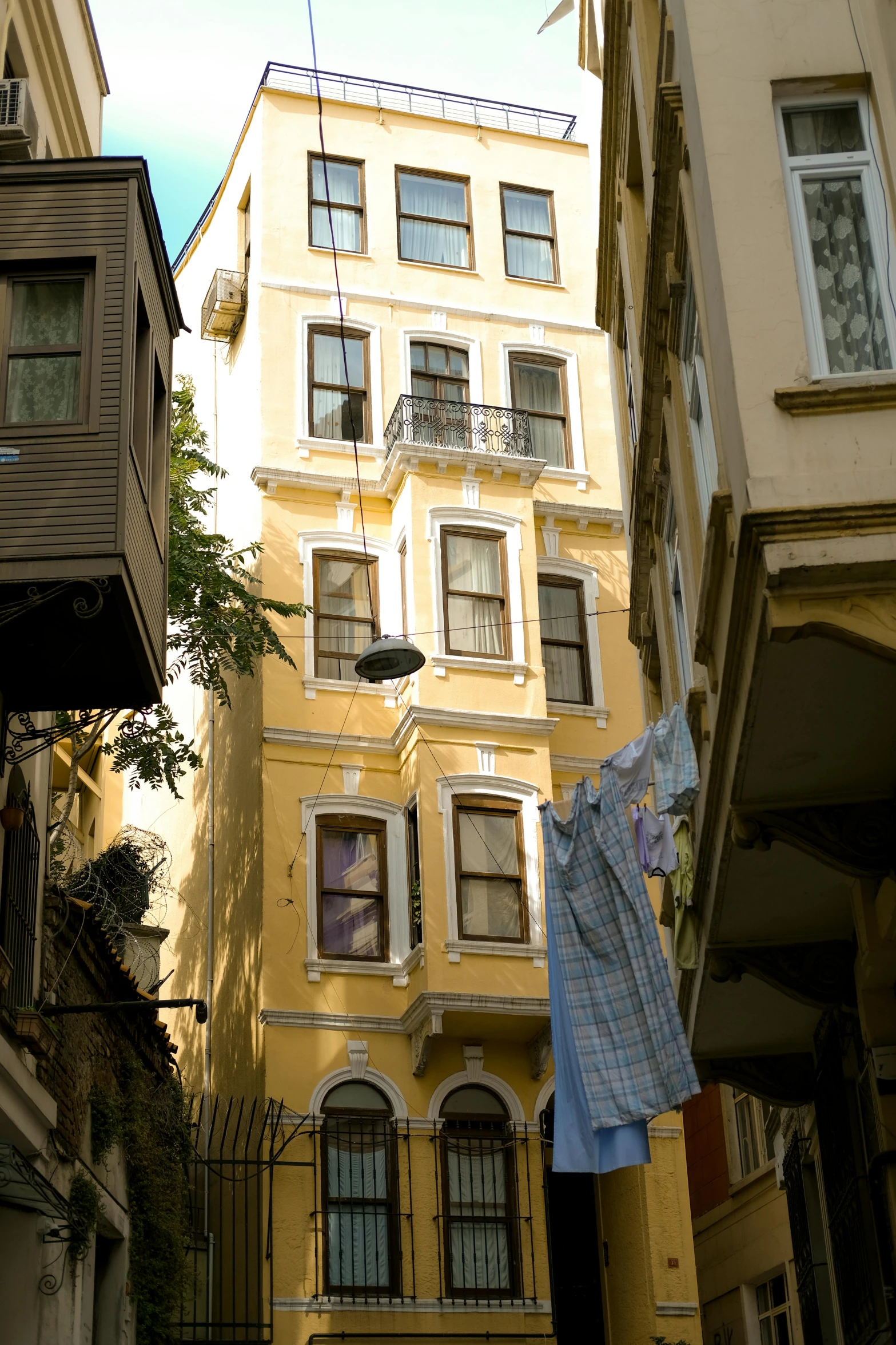 several tall buildings sit behind an alleyway with clothes hanging out to dry