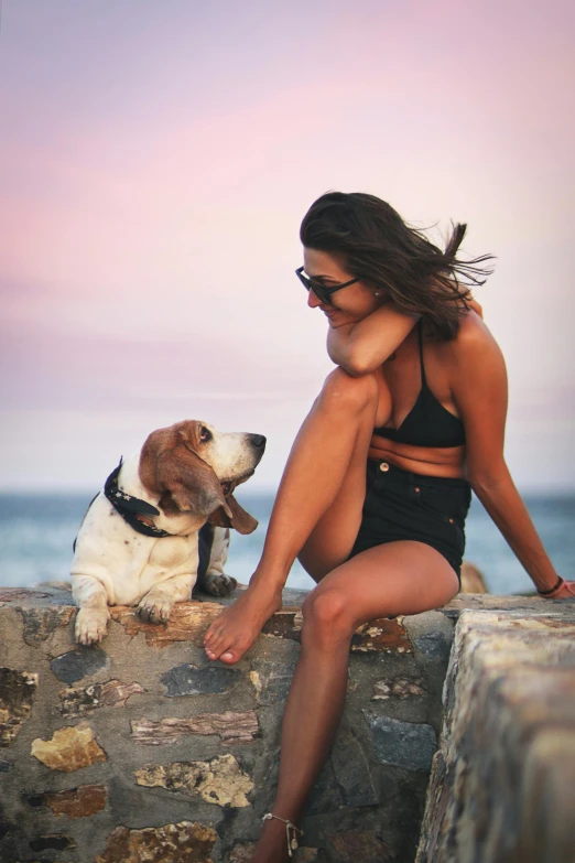 woman in bikini with her dog on the rocks