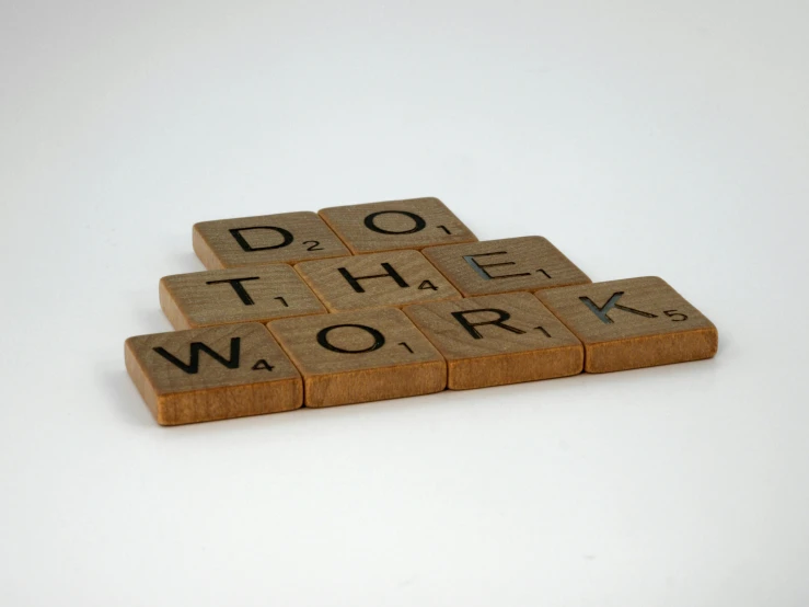 four wooden scrabbles stacked to spell do the work