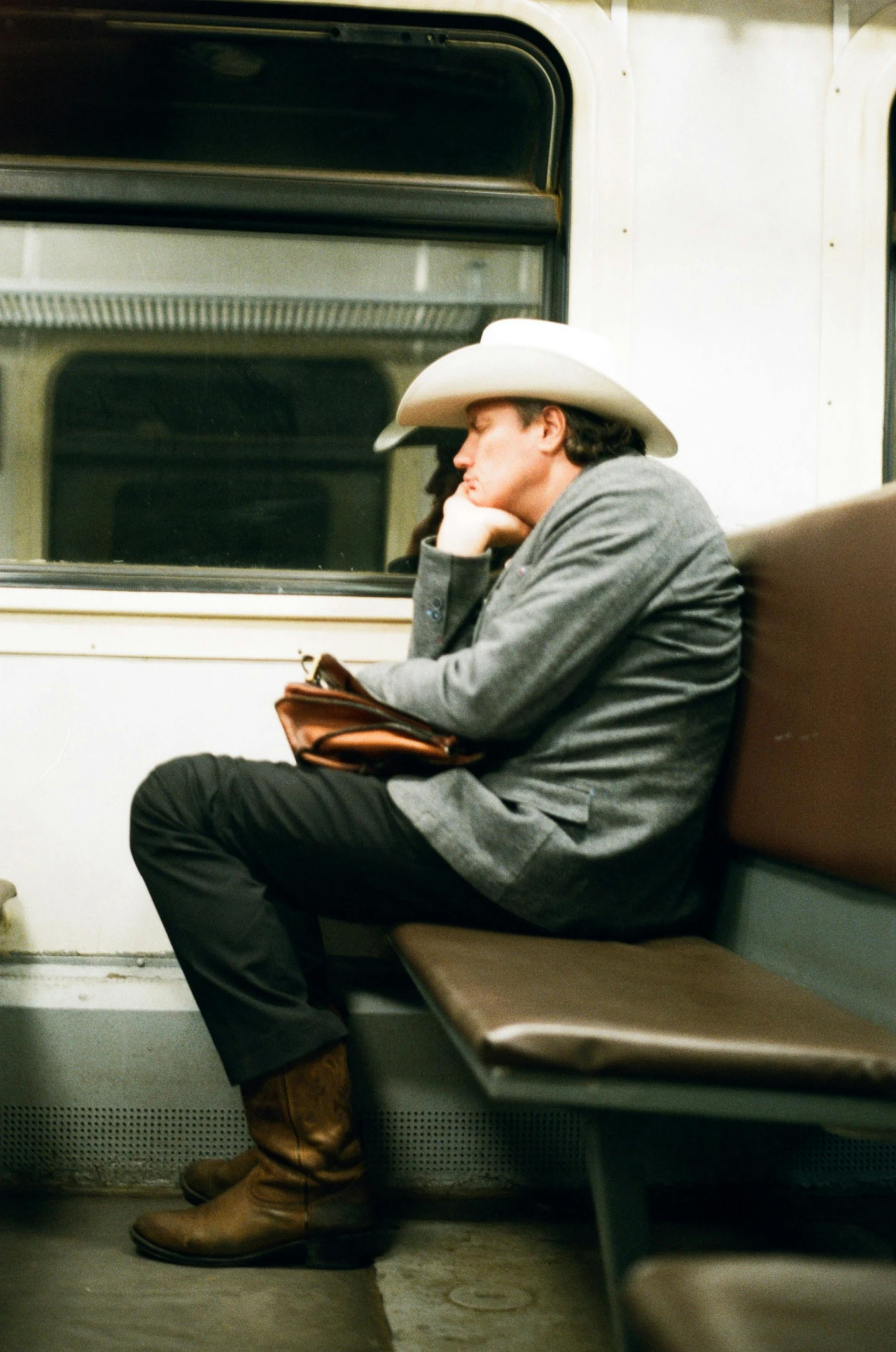 a man sitting on a subway train with his head down