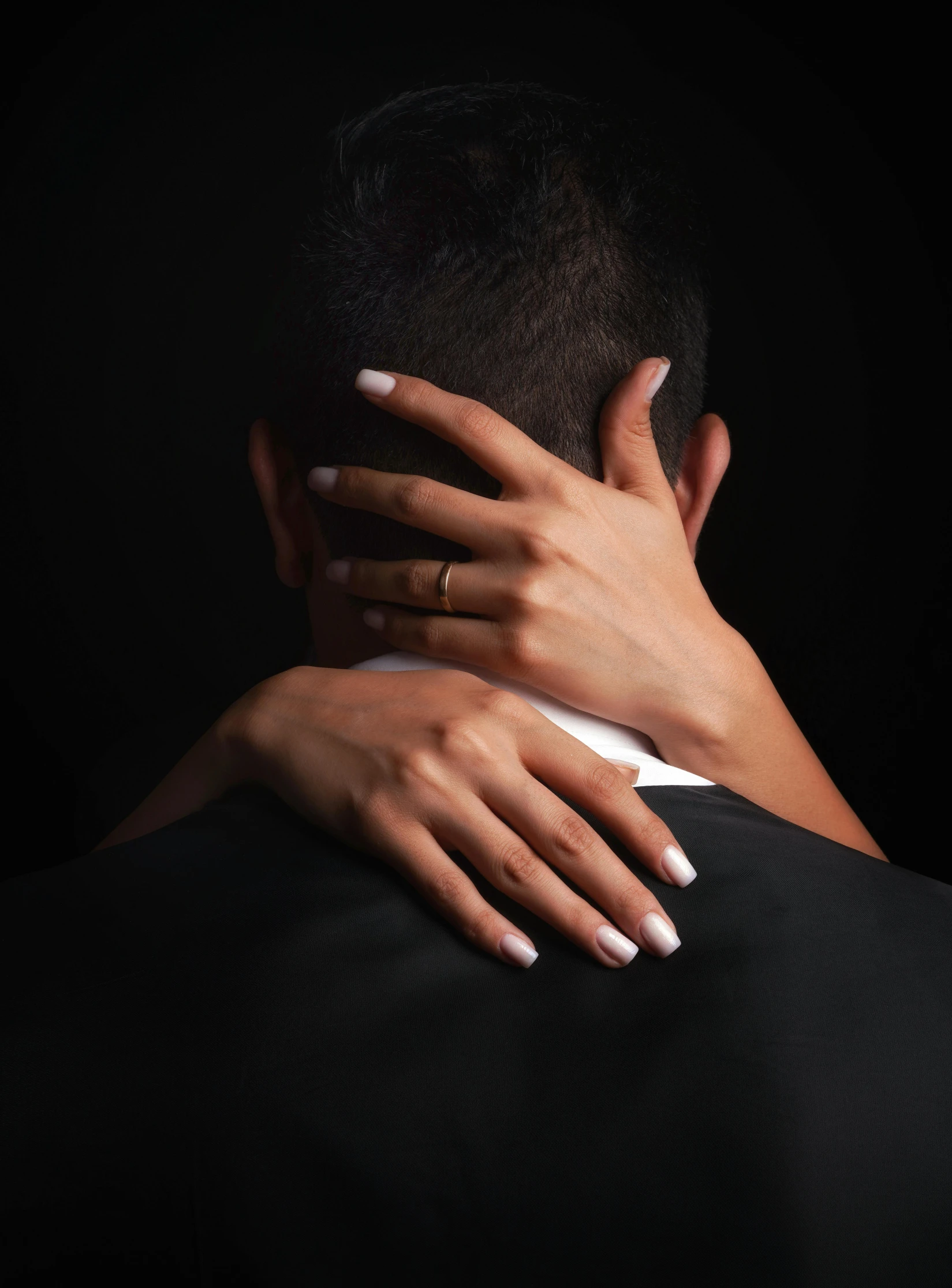 a woman hugging the neck of a black man in the dark