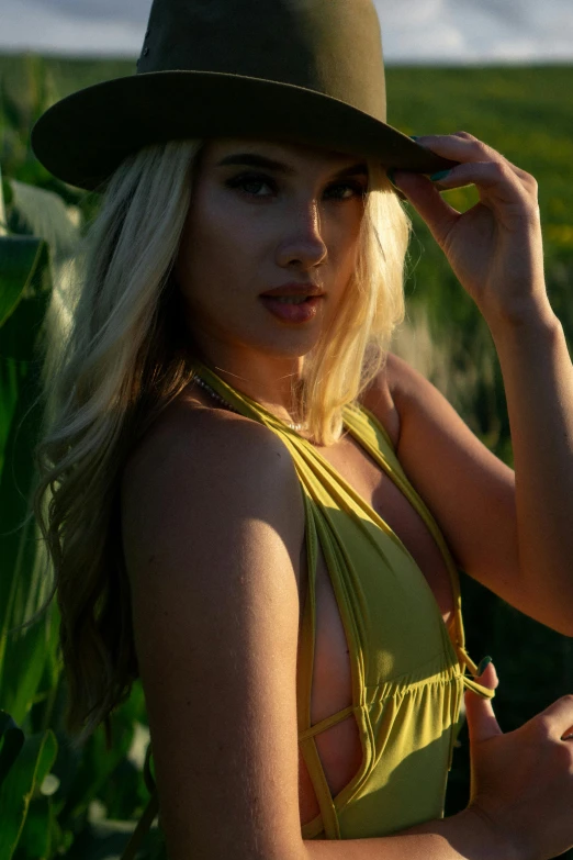 beautiful blonde woman with green hat posing for picture